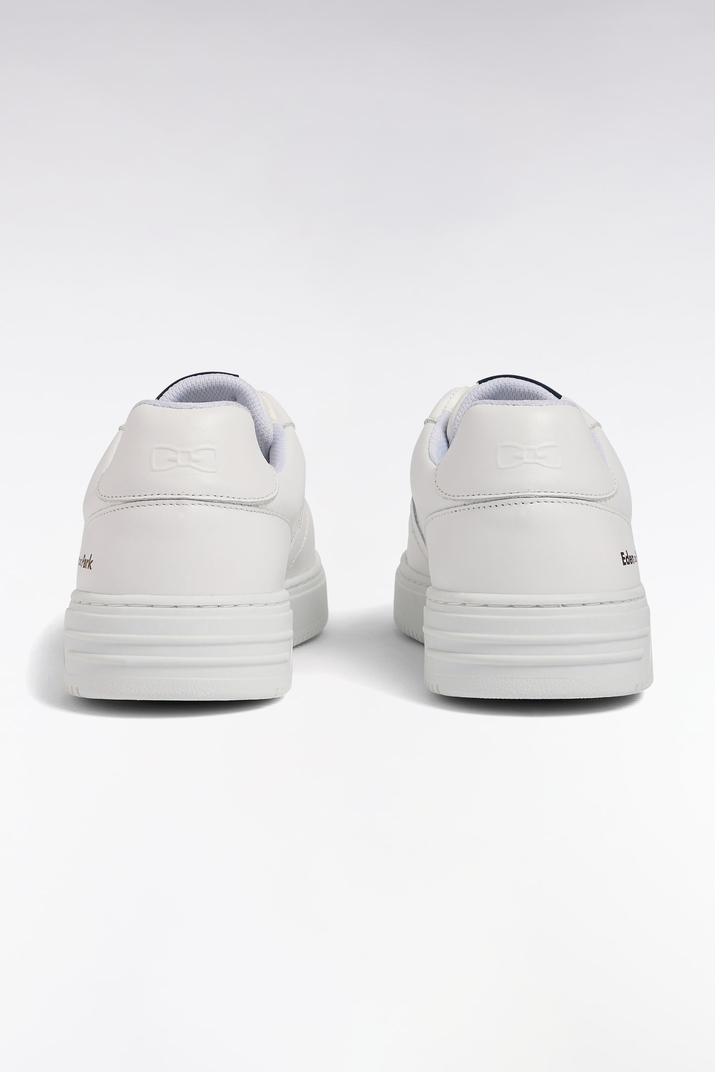 White leather sneakers with navy logo tongue